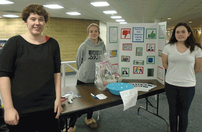 Hollyann Edwards (left) stands alongside Tri-County students Ashley Barratt and Hannah Goudreau at an informational table the trio coordinated to inform their peers about healthy coping strategies in the spring of 2016.