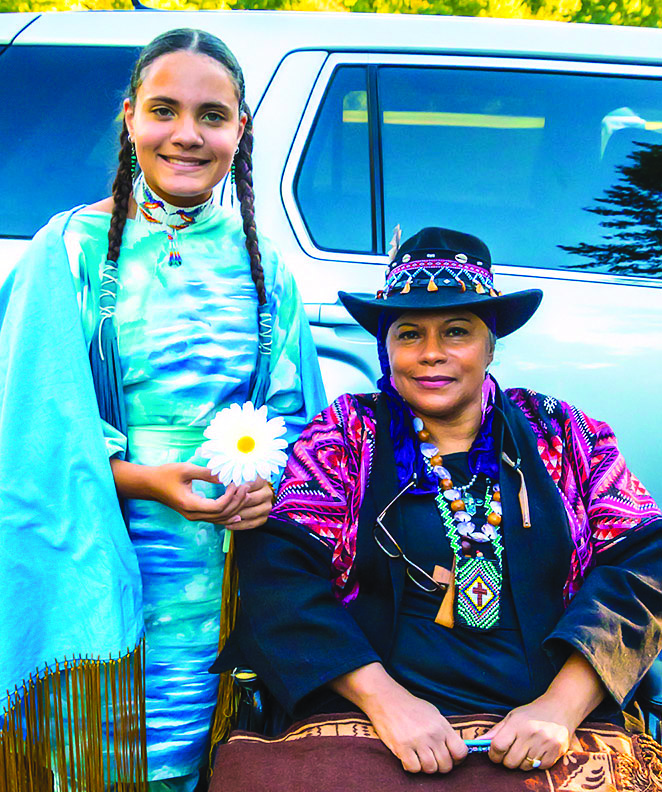 Chief Caring Hands (right) next to Keteri Tekawitha (left), who holds a daisy in honor of Rita “Daisy” Orcut of Natick’s own “Sizzling Seniors.” (Photo/Roger Gordy)